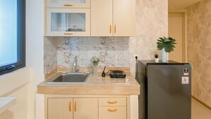 A kitchen with a marble backsplash, a sink, a refrigerator, and a potted plant.