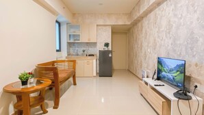 A compact kitchen with a dining area, a TV, and a small table with a plant.