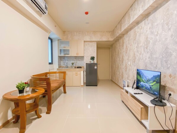 A compact kitchen with a dining area, a TV, and a small table with a plant.