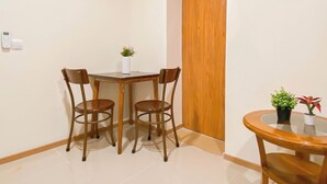 A small dining area with a wooden table and four chairs, a small potted plant, and a wooden door.