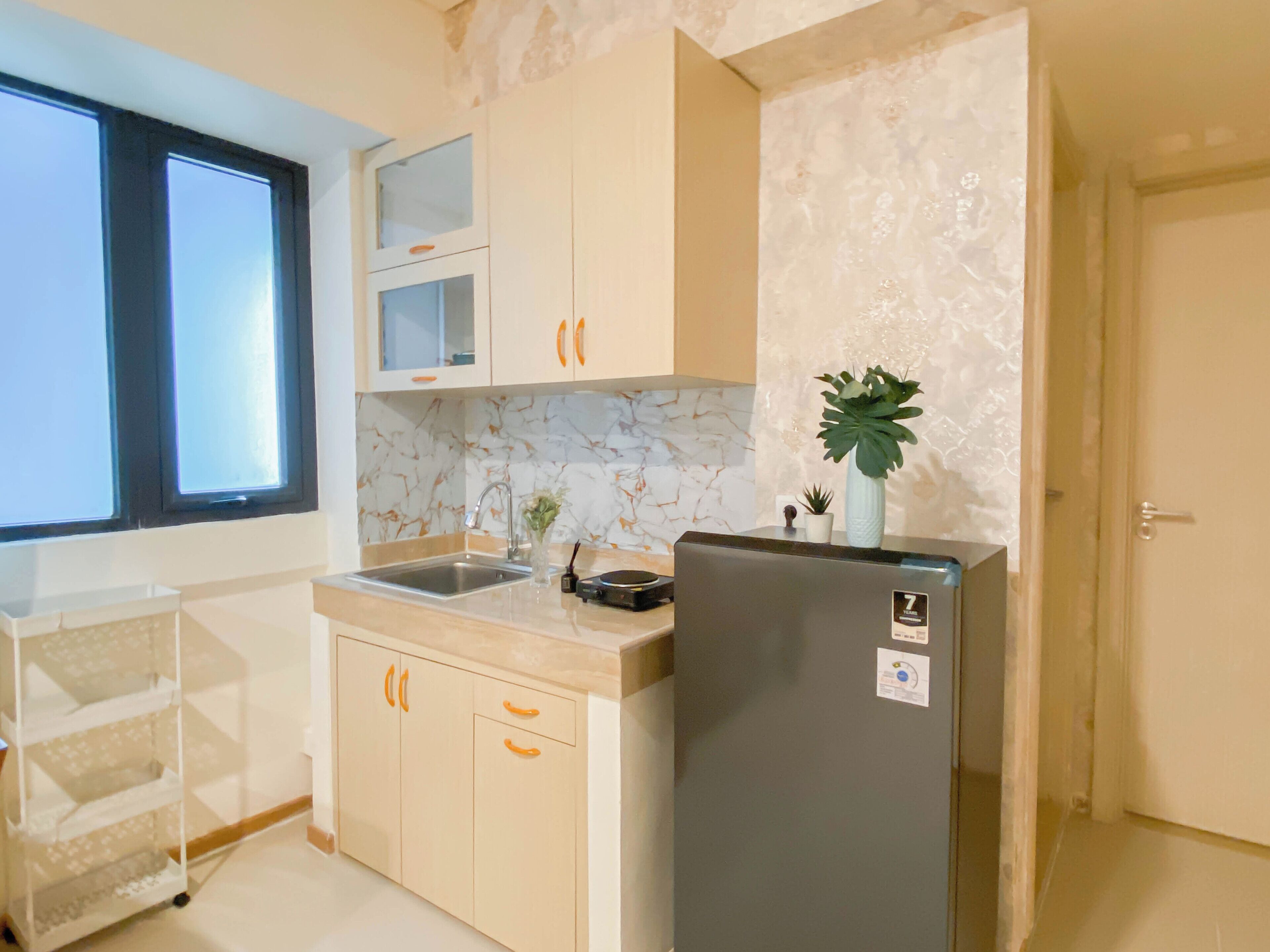 A kitchen with a marble backsplash, a refrigerator, a sink, and a window.