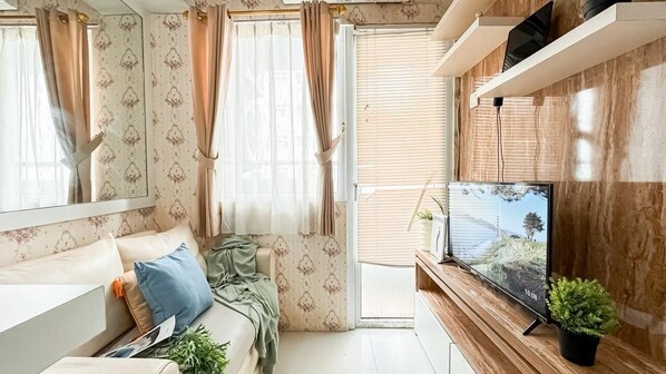 A modern living room with a sofa, TV, and a plant.