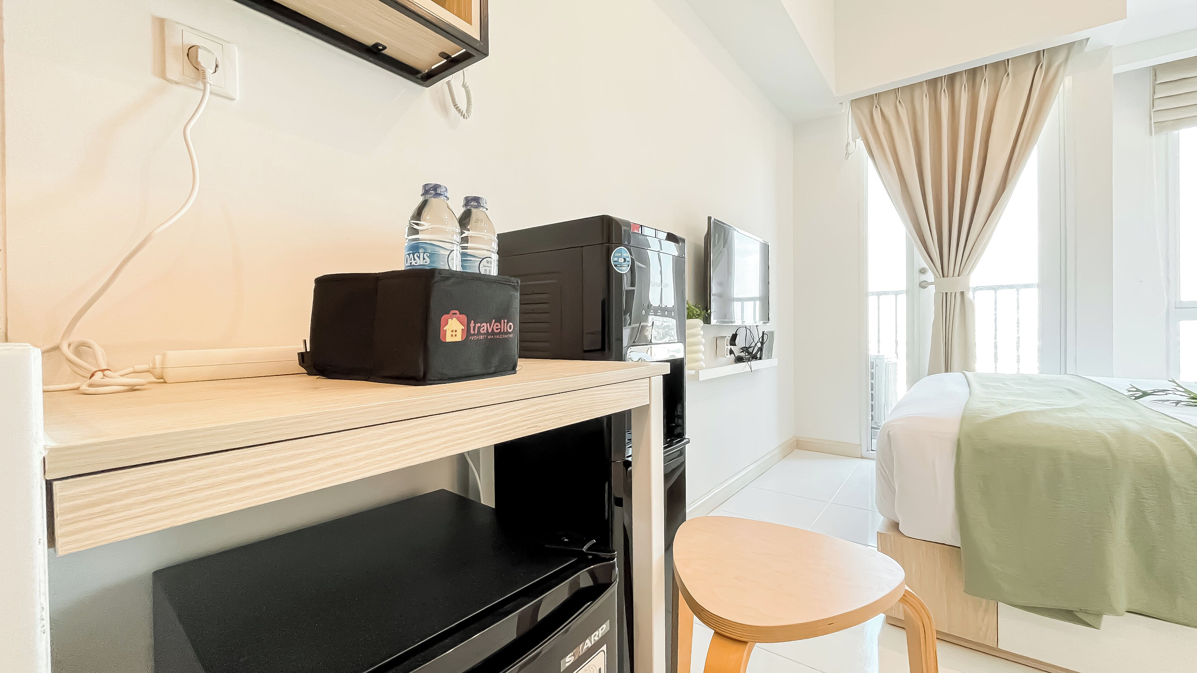 A hotel room with a desk, a coffee machine, a water dispenser, and a bed.