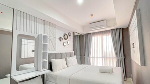 Una habitación de hotel moderna con una cama grande, un armario empotrado, una mesita de noche con espejo y una ventana con cortinas.