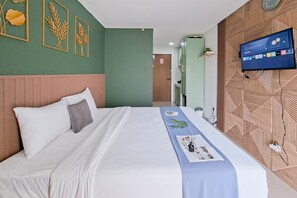 Una camera d'albergo con un letto, una TV fissata al muro e pannelli di legno decorativi.