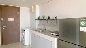 Eine kleine Küche mit Waschmaschine, Spüle und Kühlschrank.
