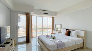 Ein Hotelzimmer mit Bett, Fernseher, Schreibtisch und einem großen Fenster mit Vorhängen.