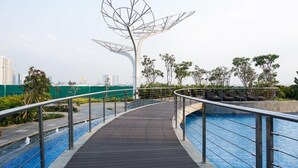 A rooftop pool area with a modern metal sculpture, lounge chairs, and a view of the city skyline. - Spacious Studio Apartment West Vista Near Rawa Buaya Station (Jakarta)