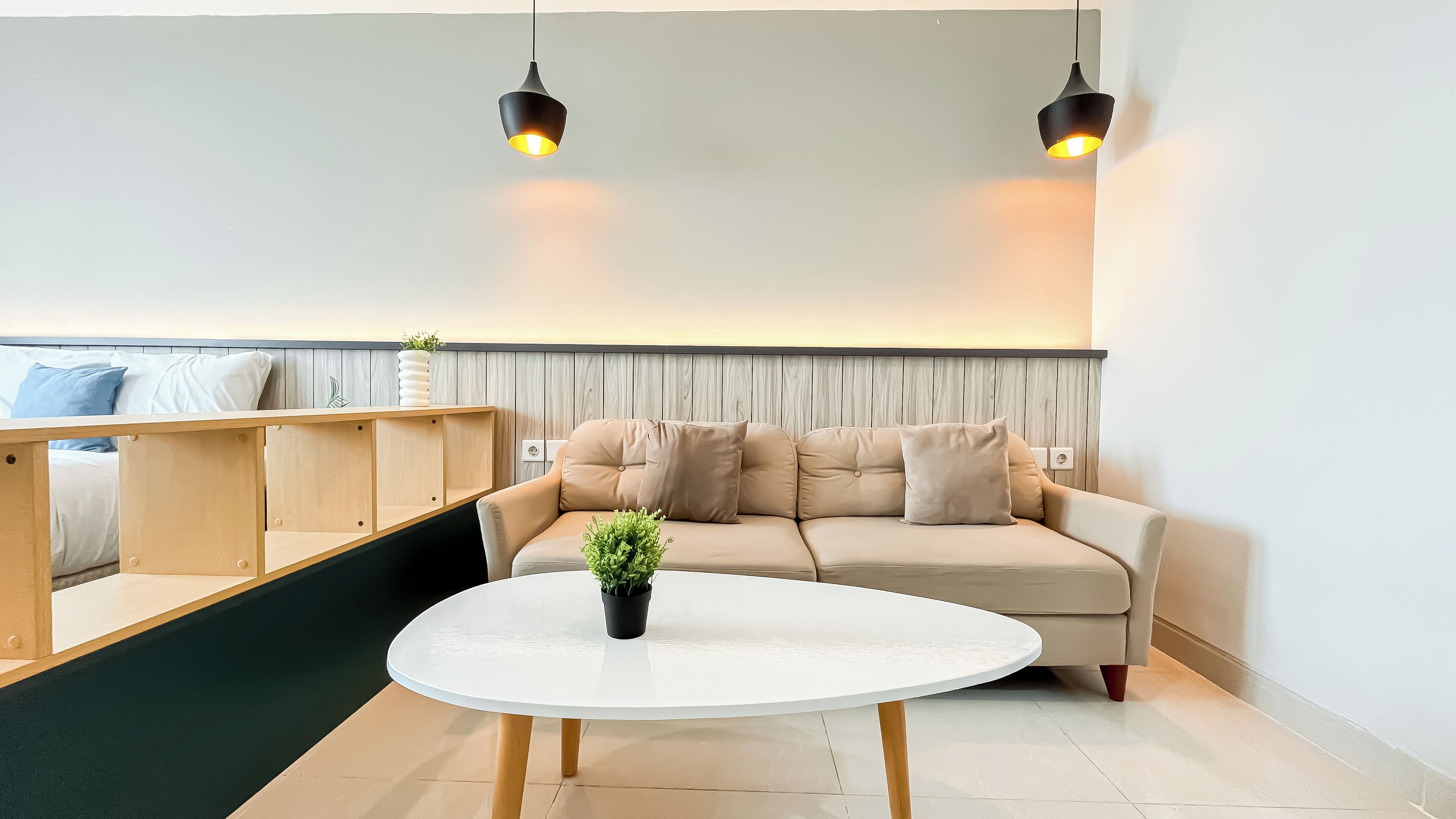 A modern living room with a beige sofa, a white coffee table, and two pendant lights.