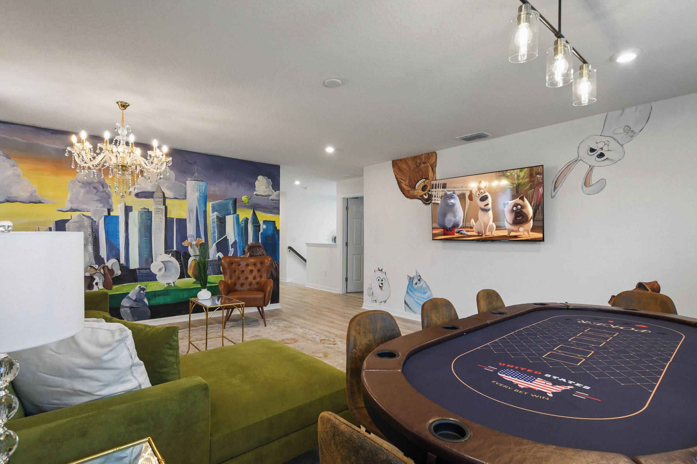 Una habitación con mesa de billar, sofás verdes, una lámpara de araña y un mural de paisaje urbano.