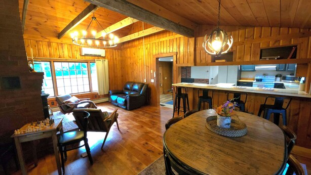A cozy cabin interior with a dining area, a living room with a fireplace, and a kitchen.