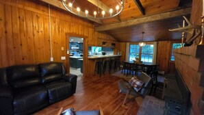 A cozy cabin interior with a living room, dining area, and kitchen.