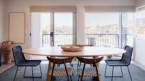 A dining area with a round table, four chairs, a vase, and a view of the city through large windows. - Luxe Retreat in Battery Point (Battery Point)