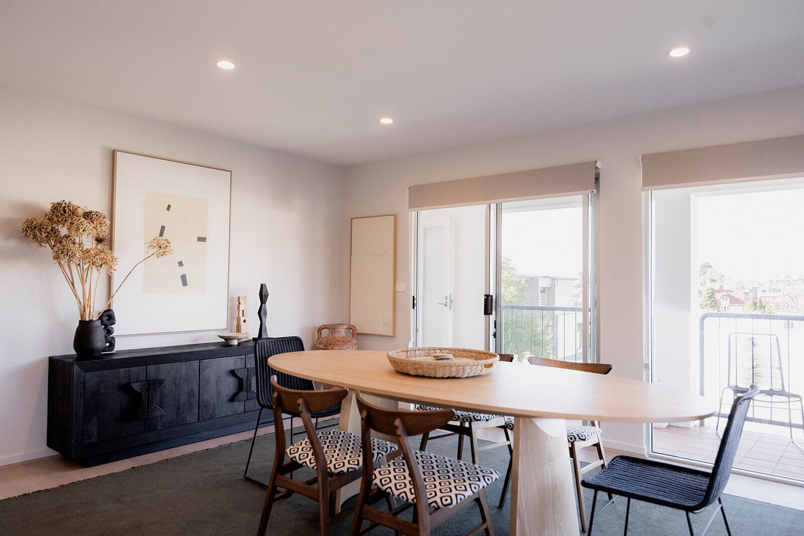 Un coin repas avec une table ronde, des chaises, un buffet noir et des œuvres d’art encadrées accrochées au mur.