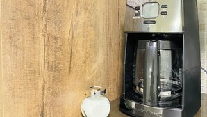 Une enseigne indiquant un café sur un mur en bois, une machine à café et une carafe en verre sur un comptoir.