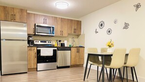 Une cuisine moderne dotée d’appareils électroménagers en acier inoxydable, de meubles en bois et d’un coin repas avec une table et des chaises.