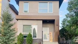 Une maison moderne à deux étages, avec une entrée à l’avant, un petit jardin et une boîte aux lettres.