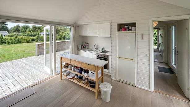 Cozinha moderna com ilha de madeira, armários brancos e vista para o jardim.