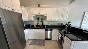 A modern kitchen with white cabinets, stainless steel appliances, and a black countertop. - Golf, Beach & Great Local Eats! This condo unit is minutes is away from it all. (Breadalbane)
