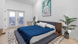 A bedroom with a large bed, a ceiling fan, a window with blinds, a potted plant, and a Buddha statue on the wall. - 3/3 sauna, arcade, play couch, 70" TV, fire pit, balconies, 6 min from downtown (Chattanooga)