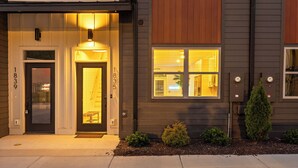A modern two-story house with a dark exterior, a front door with a glass panel, and a small front yard with a few shrubs. - 3/3 sauna, arcade, play couch, 70" TV, fire pit, balconies, 6 min from downtown (Chattanooga)