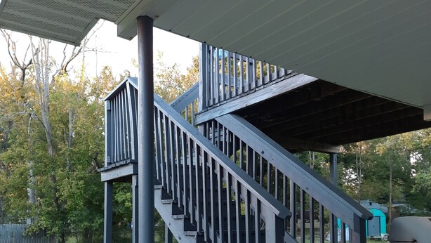Un escalier extérieur abrité, doté d’une rampe en métal, qui mène à une terrasse.