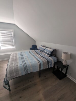 A bedroom with a bed, a nightstand, a lamp, and a window with blinds. - Cozy, pet-friendly, 1-bedroom apartment in Oak Ridge with AC (Oak Ridge)