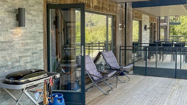 A modern outdoor patio with a grill, lounge chairs, and a glass door leading to a deck. - 3 bedroom awesome apartment in Hemsedal (Hemsedal)