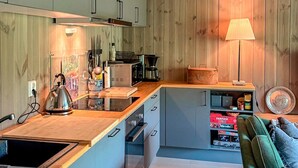A compact kitchen with wooden cabinets, a built-in stove, and a coffee machine. - 3 bedroom awesome apartment in Hemsedal (Hemsedal)