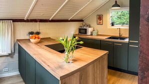 Une cuisine dotée d’un plan de travail en bois, d’un évier et d’une fenêtre donnant sur un paysage verdoyant.