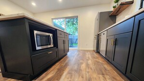 A kitchen with dark cabinetry, a microwave, and a wooden floor. - Meet Don - A Modern, Zero-step, Pet-friendly home in Rochester (Rochester)