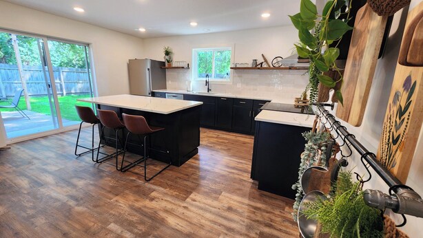 A modern kitchen with a central island, bar stools, and a view of the backyard through large sliding doors. - Meet Don - A Modern, Zero-step, Pet-friendly home in Rochester (Rochester)
