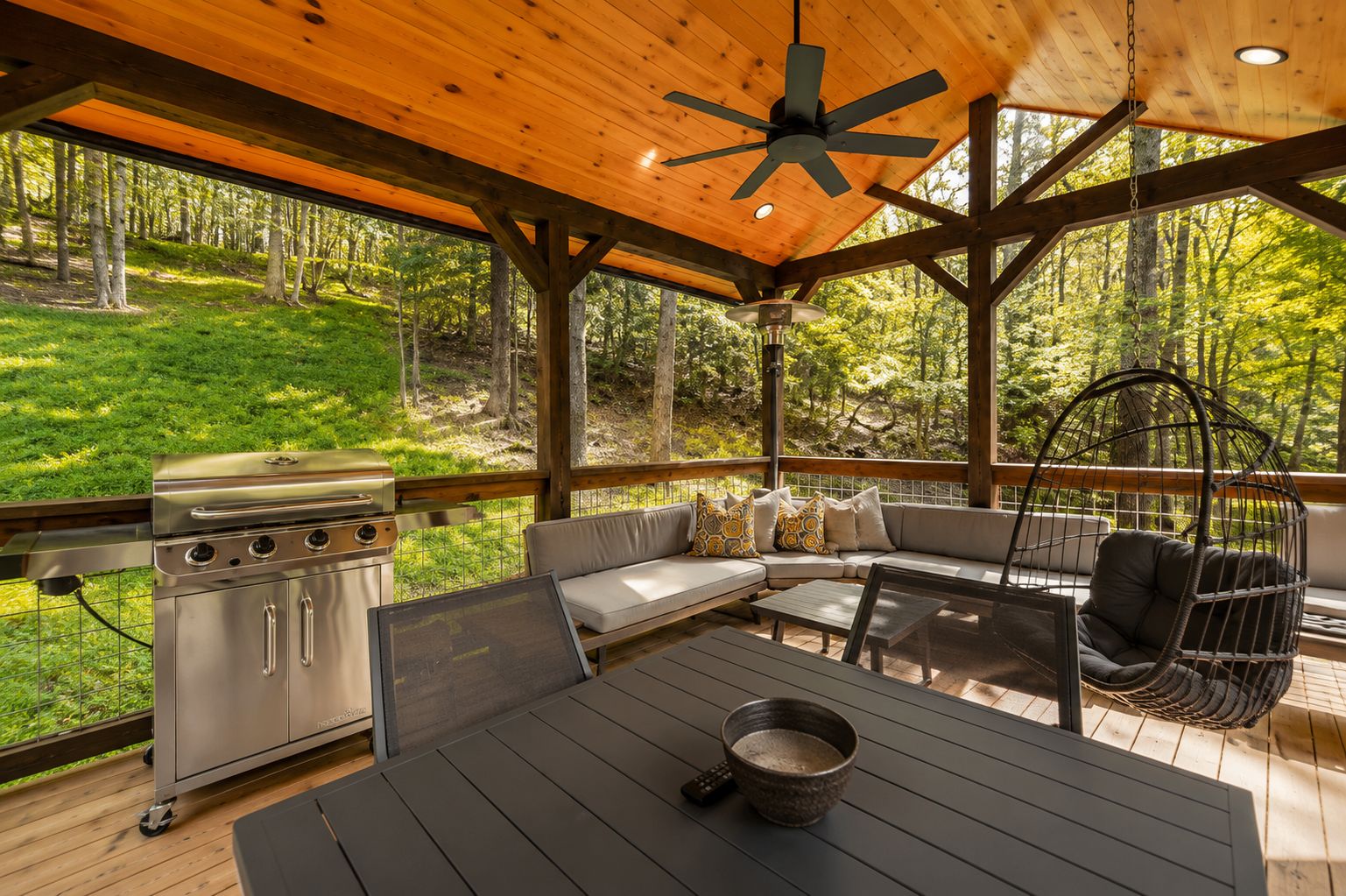 An outdoor deck with a grill, seating area, and hanging chair.