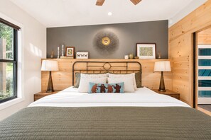 A bedroom with a bed, two bedside tables, a wall clock, and a window.