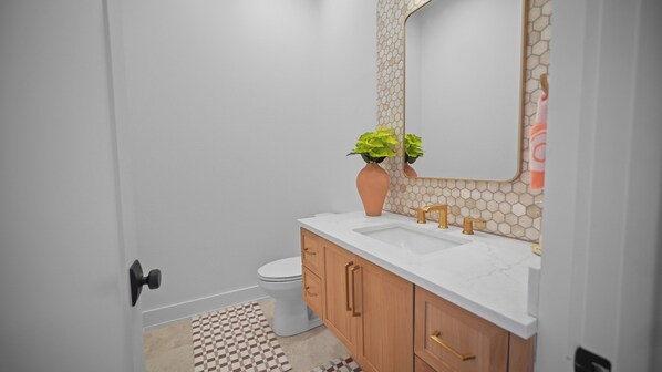 A bathroom with a white sink, a mirror, a toilet, and wooden cabinets.