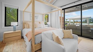 A modern bedroom with a four-poster bed, a sitting area with a chair, and a view of the outdoors. - NEW Ultra-Luxury Sandy Point Beachfront/Canal Villa Amara-introductory offerings (Sandy Point)
