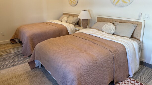 A hotel room with two beds, each with a brown bedspread, white linens, and decorative pillows. There is a nightstand with a lamp and a wall-mounted artwork. - NEW Ultra-Luxury Sandy Point Beachfront/Canal Villa Amara-introductory offerings (Sandy Point)