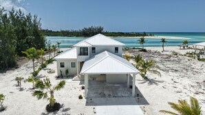 A beachfront property with a two-story house, a covered patio, and a sandy beach. - NEW Ultra-Luxury Sandy Point Beachfront/Canal Villa Amara-introductory offerings (Sandy Point)