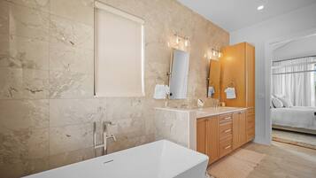 A modern bathroom with a bathtub, double vanity, and a large mirror.
