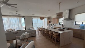 A modern kitchen with a central island, bar stools, and a dining area with a sofa and chairs.
