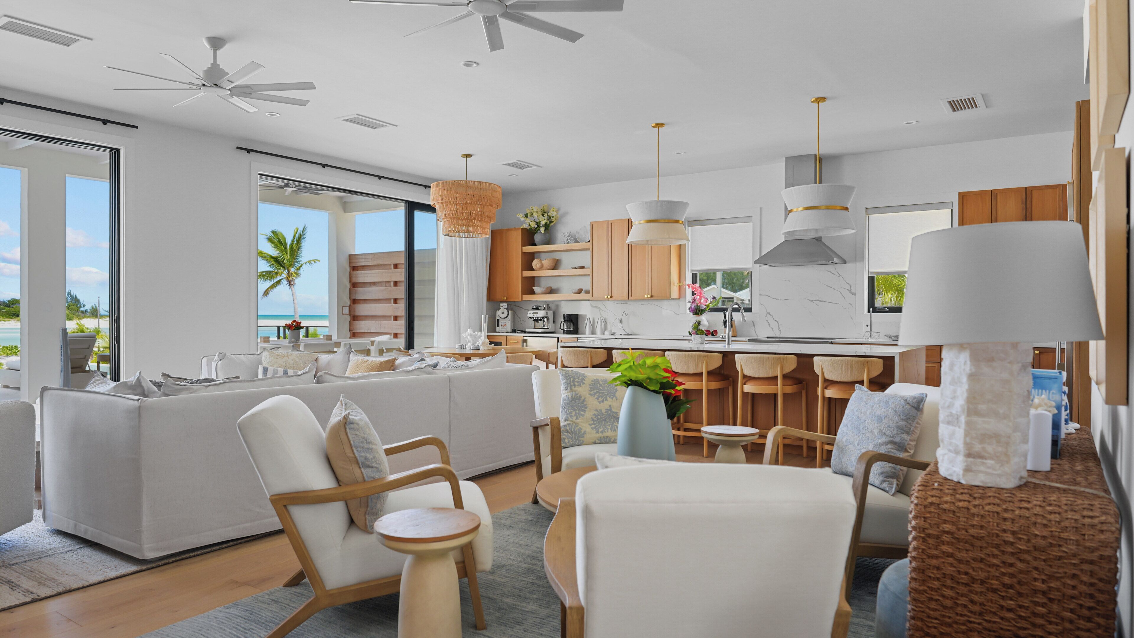 A modern kitchen with a central island, bar seating, and a view of the beach.