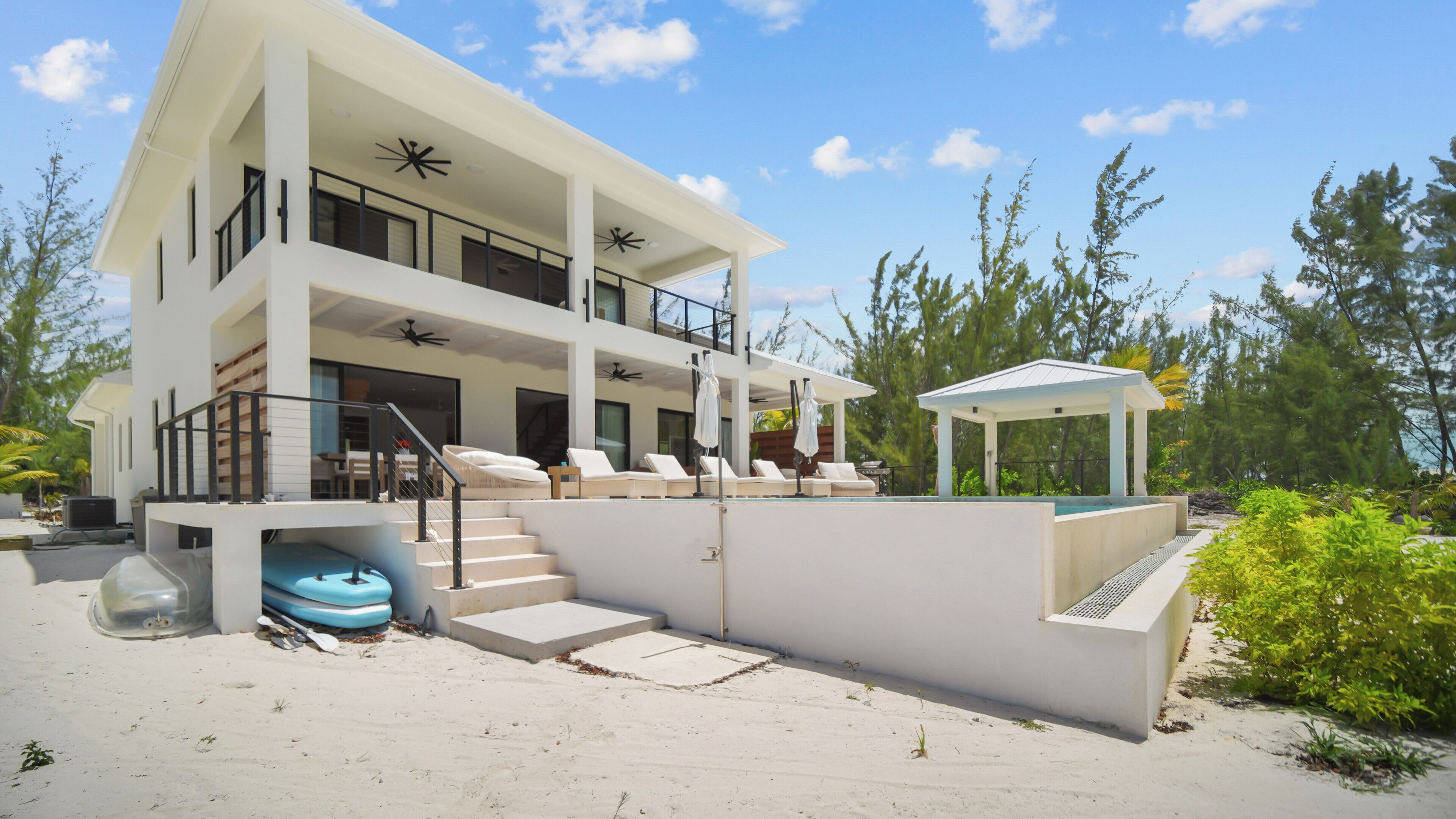 Un edificio moderno de varios pisos con piscina, zona de estar exterior y un área cubierta.