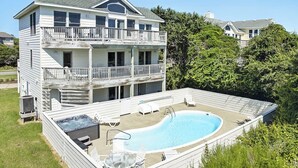 Ett tvåvåningshus med en swimmingpool, utomhusmöbler och en bubbelpool.