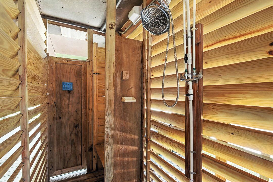Un intérieur en bois avec un espace douche, comprenant un pommeau de douche et des tuyaux.