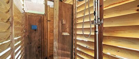 Un intérieur en bois avec un espace douche, comprenant un pommeau de douche et des tuyaux.