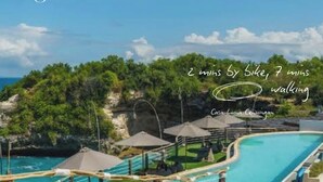 Zona de piscina con una vista despejada del paisaje circundante, que incluye árboles y una lejana vista al mar.