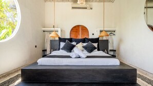 Un dormitorio con una cama grande, dos mesitas de noche, un cabecero arqueado de madera y una lámpara colgante.