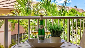 A bottle of Havemeyer wine, two glasses, and a potted plant on a balcony with a railing. - Tropical stay with full kitchen (Kihei)