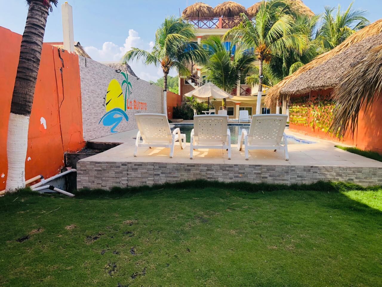 A patio area with outdoor seating, a pool, and a thatched-roof structure.