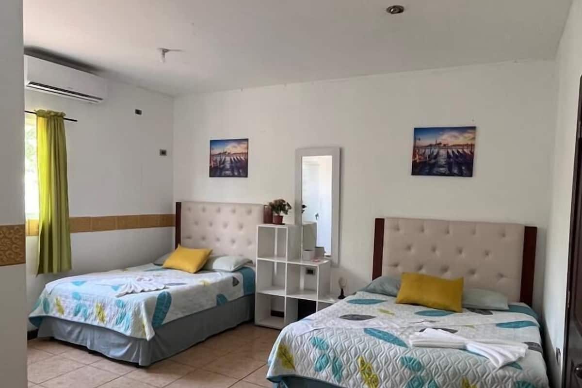 Habitación de hotel con dos camas, un pequeño armario blanco y un espejo.